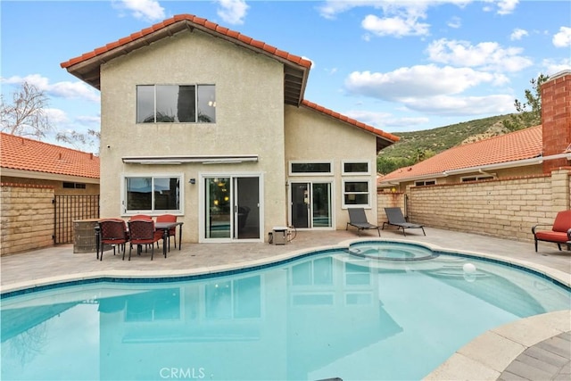 rear view of house featuring a tiled roof, fence, a patio, stucco siding, and a pool with connected hot tub