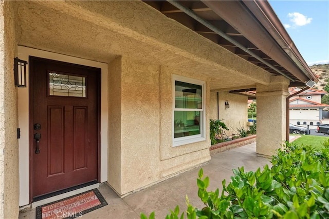 doorway to property with a porch and stucco siding