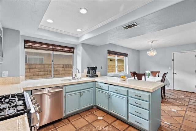 kitchen with a peninsula, a sink, visible vents, appliances with stainless steel finishes, and a raised ceiling