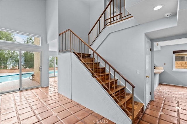 staircase featuring tile patterned floors and a towering ceiling