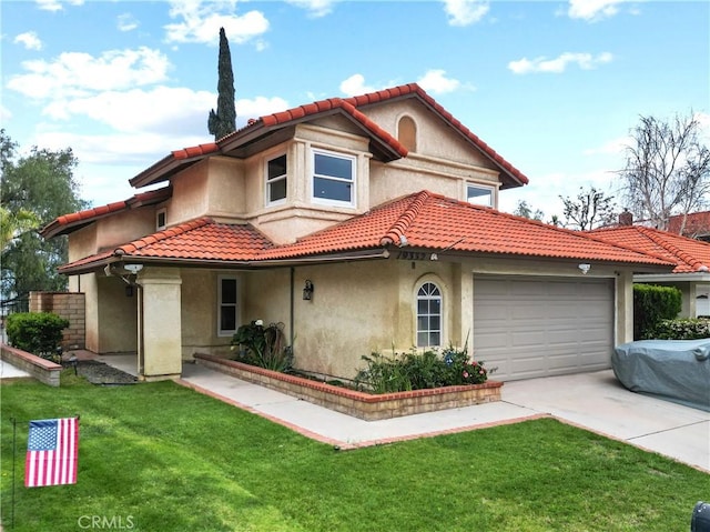 mediterranean / spanish house with a tile roof, a front lawn, driveway, an attached garage, and stucco siding