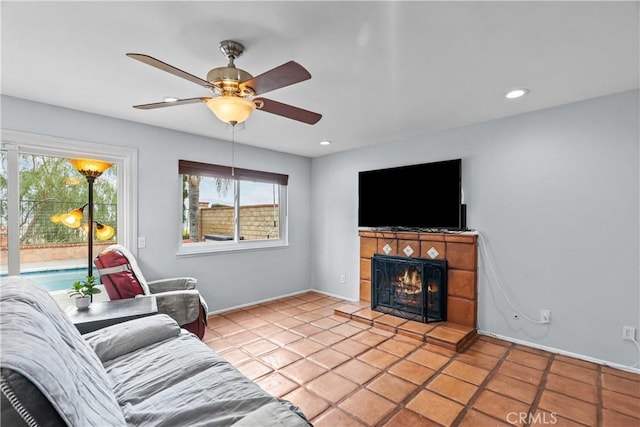 living area with a ceiling fan, baseboards, a tile fireplace, and recessed lighting