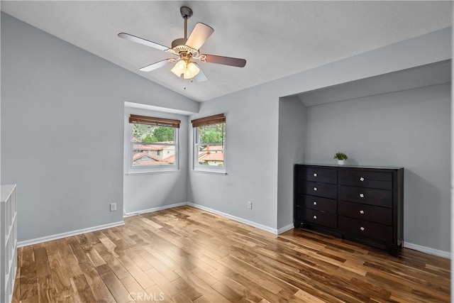 unfurnished bedroom featuring lofted ceiling, baseboards, a ceiling fan, and wood finished floors