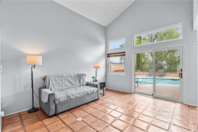 living area with baseboards and high vaulted ceiling