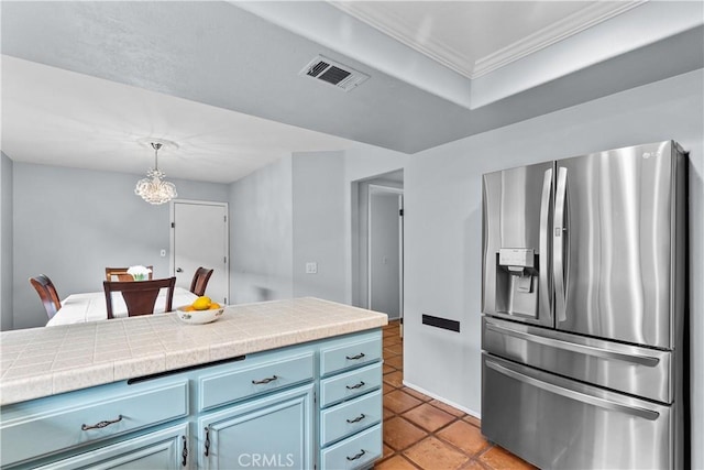 kitchen featuring blue cabinets, stainless steel fridge, an inviting chandelier, tile counters, and ornamental molding