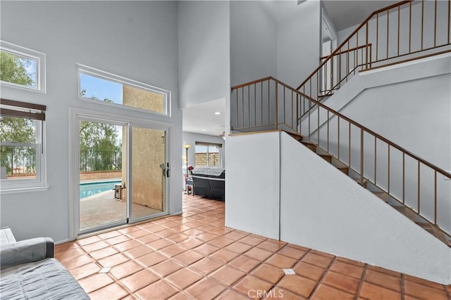 unfurnished living room featuring stairway, a high ceiling, and tile patterned floors