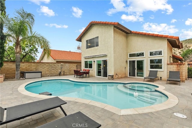 view of swimming pool featuring fence, a patio area, and a pool with connected hot tub