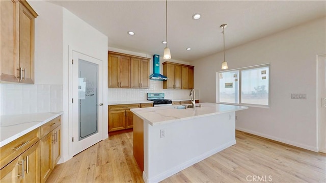 kitchen featuring backsplash, stainless steel range with gas cooktop, light wood-style flooring, and wall chimney range hood