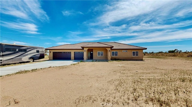 prairie-style home featuring stucco siding, a tile roof, driveway, and a garage