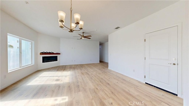 unfurnished living room featuring visible vents, light wood-type flooring, baseboards, a fireplace, and ceiling fan with notable chandelier