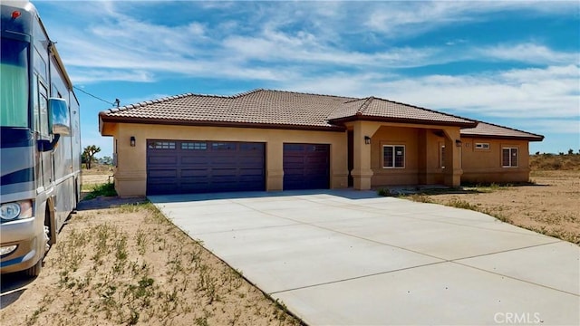 view of front facade with a tile roof, an attached garage, stucco siding, and driveway