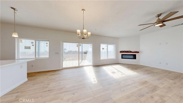 unfurnished living room with light wood-style floors, visible vents, baseboards, and ceiling fan with notable chandelier