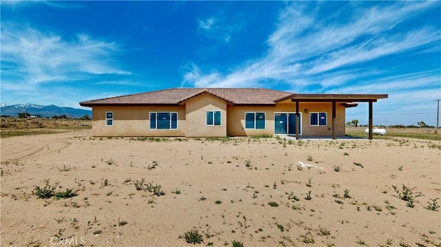 rear view of property featuring a tile roof, stucco siding, and a mountain view