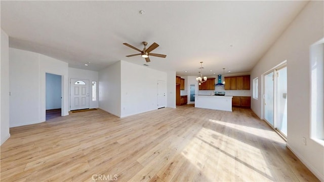 unfurnished living room featuring ceiling fan with notable chandelier and light wood-type flooring