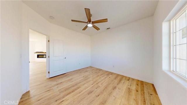 unfurnished room with ceiling fan, baseboards, and light wood-style floors