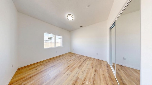 unfurnished bedroom with a closet, light wood finished floors, baseboards, and visible vents
