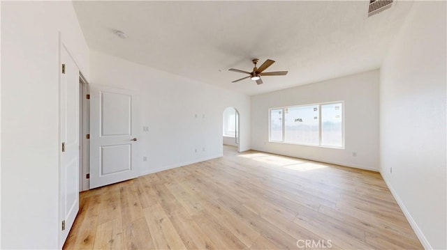unfurnished room featuring light wood-type flooring, ceiling fan, arched walkways, baseboards, and visible vents