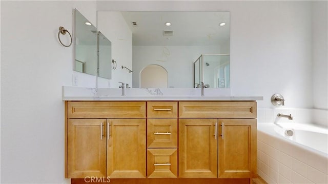 bathroom featuring recessed lighting, a shower with shower door, double vanity, visible vents, and a garden tub