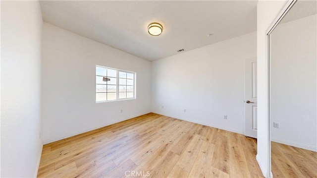 spare room with baseboards, visible vents, and light wood finished floors