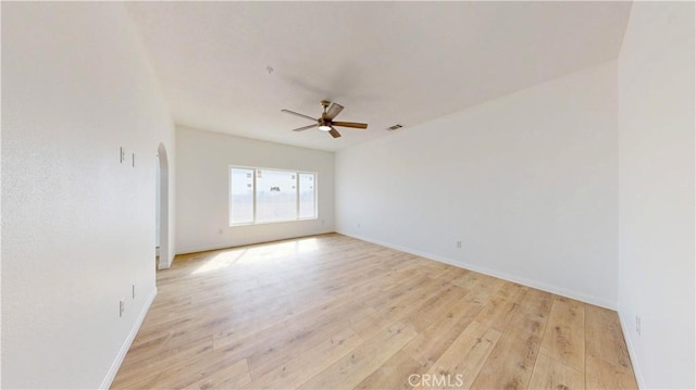 unfurnished room featuring arched walkways, light wood-style flooring, visible vents, and a ceiling fan