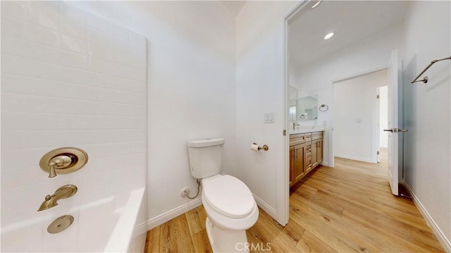 full bath featuring wood finished floors, vanity,  shower combination, baseboards, and toilet