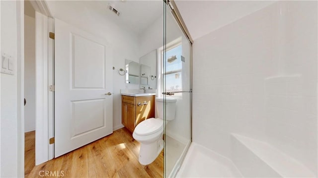 bathroom with wood finished floors, visible vents, vanity, and a walk in shower