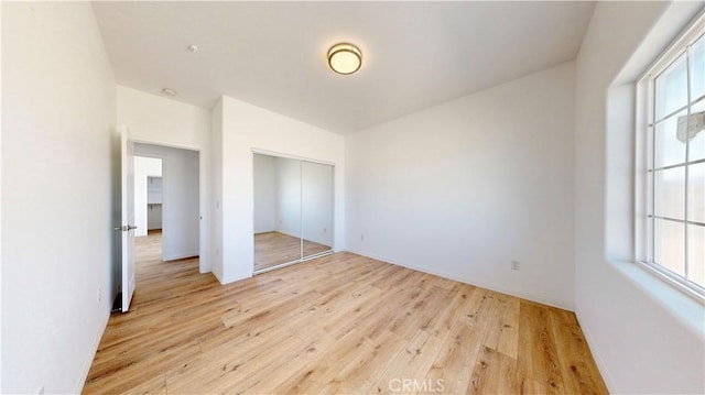 unfurnished bedroom featuring light wood-style floors and a closet