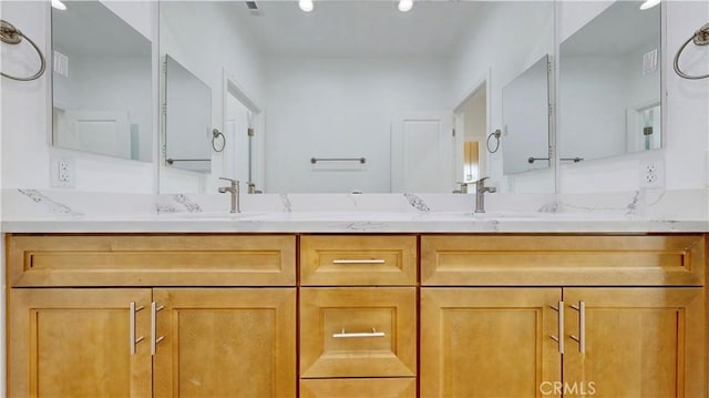 bathroom with visible vents, a sink, and double vanity