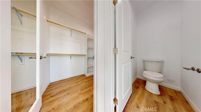 bathroom with baseboards, wood finished floors, and toilet