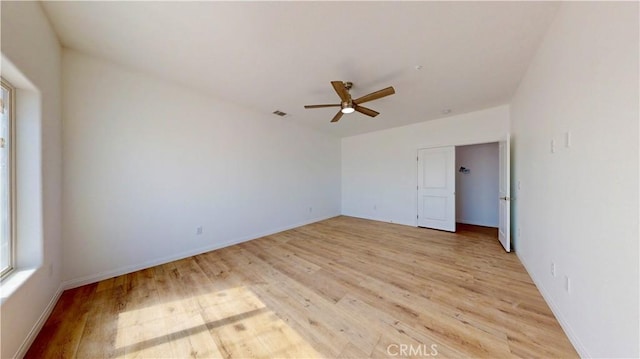 empty room featuring light wood finished floors, a ceiling fan, and baseboards