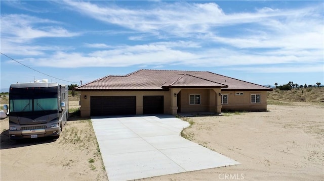 ranch-style house with stucco siding, a tile roof, driveway, and a garage