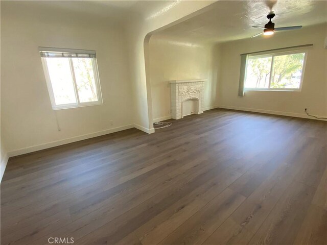 5101 Lindsey Ave, Pico Rivera, CA 90660 - unfurnished living room with dark wood-style flooring, a brick fireplace, baseboards, arched walkways, and ceiling fan