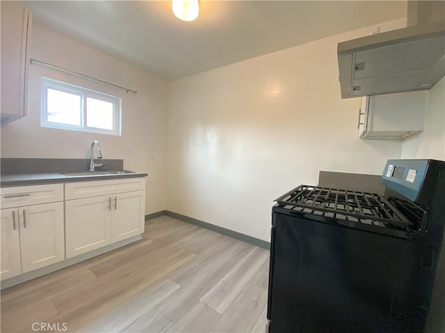 5101 Lindsey Ave, Pico Rivera, CA 90660 - kitchen with black gas stove, a sink, white cabinetry, light wood-style flooring, and baseboards