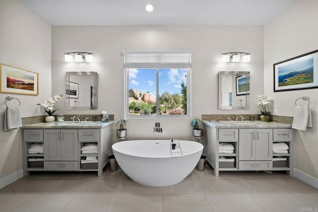 bathroom featuring a soaking tub, two vanities, and a sink