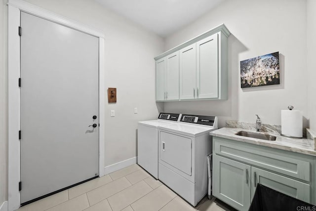 washroom with washer and dryer, cabinet space, a sink, baseboards, and light tile patterned flooring
