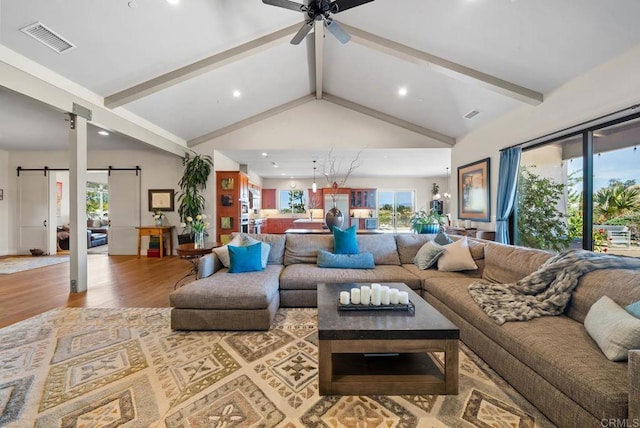 living room with recessed lighting, wood finished floors, lofted ceiling with beams, a barn door, and visible vents