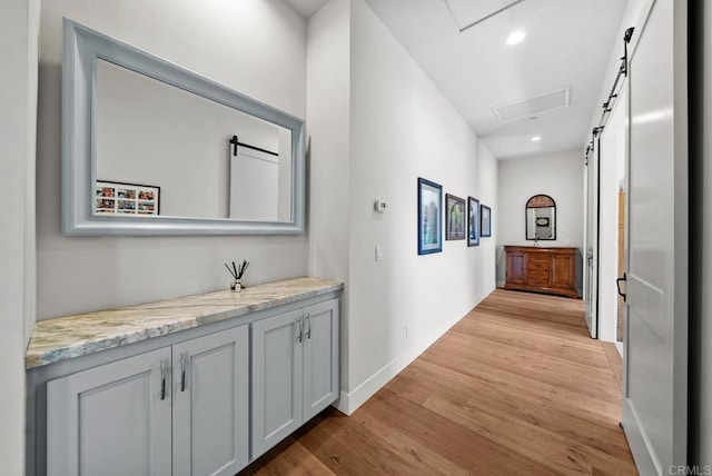 corridor with baseboards, visible vents, light wood-style floors, and recessed lighting