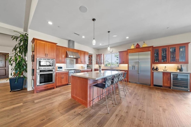 kitchen featuring beverage cooler, brown cabinets, light wood-style flooring, and built in appliances
