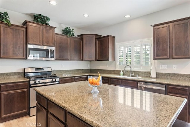 14917 Landerwood Dr, Eastvale, CA 92880 - kitchen with appliances with stainless steel finishes, a sink, light stone counters, recessed lighting, and dark brown cabinetry