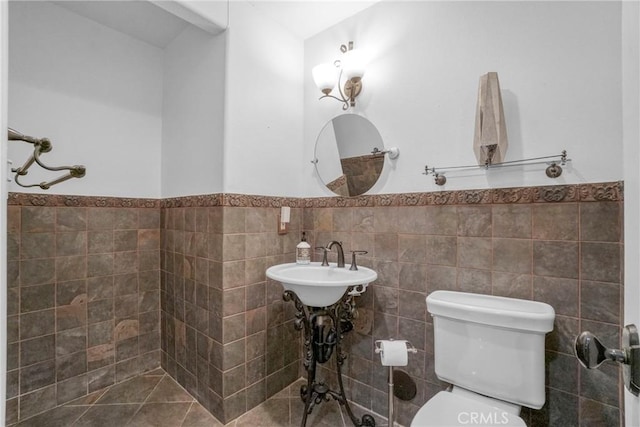bathroom with toilet, tile walls, and wainscoting