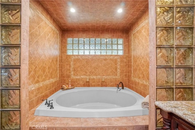 bathroom featuring recessed lighting, tile walls, and a garden tub