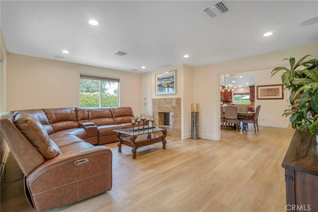living room featuring light wood finished floors, visible vents, baseboards, and a premium fireplace