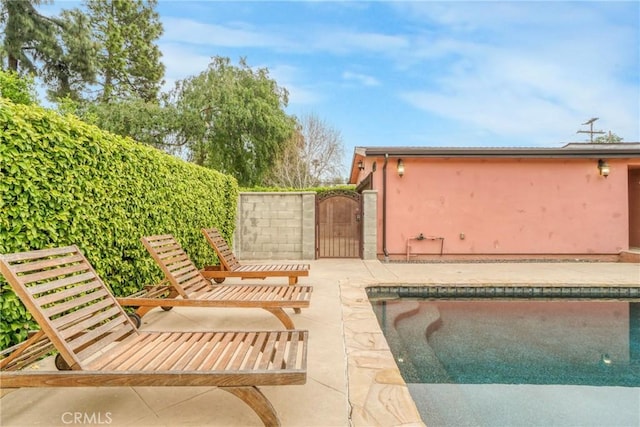 outdoor pool with a patio and a gate
