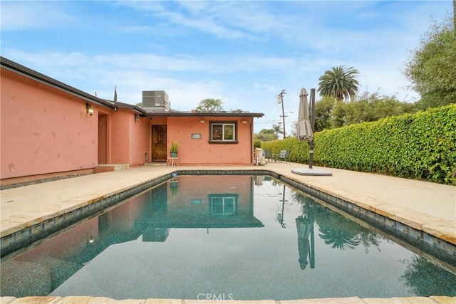 outdoor pool with central AC unit and a patio area