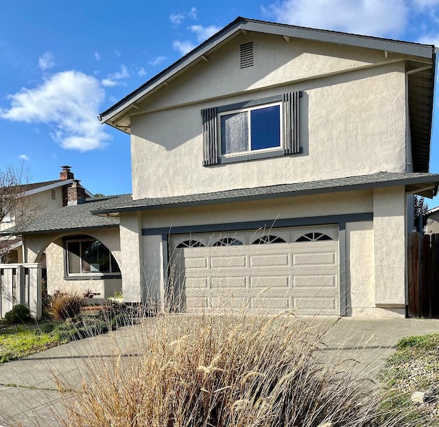 traditional-style house with a garage, stucco siding, and fence