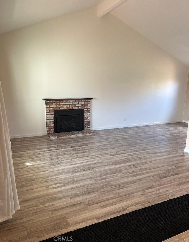 unfurnished living room featuring high vaulted ceiling, a fireplace, wood finished floors, baseboards, and beamed ceiling