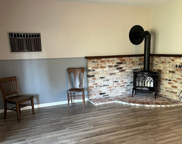 unfurnished room with wood finished floors and a wood stove