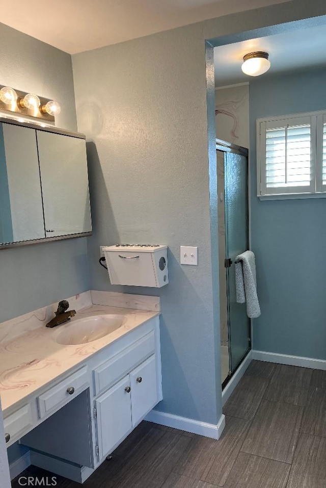bathroom with vanity, a stall shower, baseboards, and wood finished floors