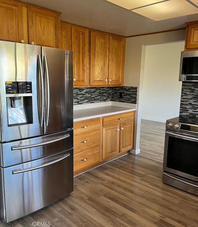 kitchen with dark wood finished floors, light countertops, tasteful backsplash, and appliances with stainless steel finishes