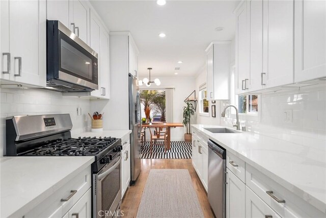 2410 Exposition Pl, Los Angeles, CA 90018 - kitchen featuring appliances with stainless steel finishes, light wood-type flooring, white cabinetry, decorative backsplash, and recessed lighting